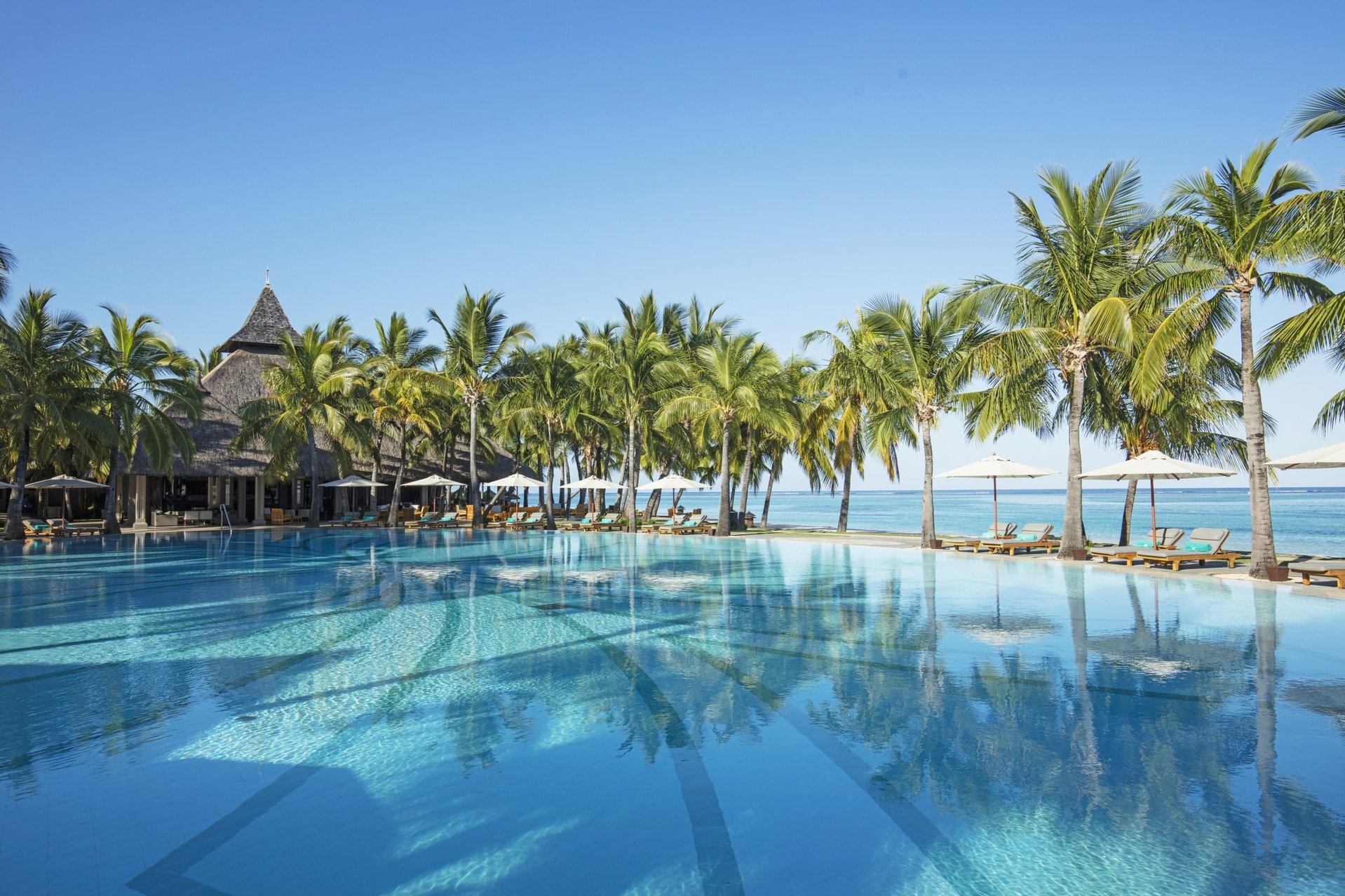 Pool mit Palmen gesäumt direkt am Meer