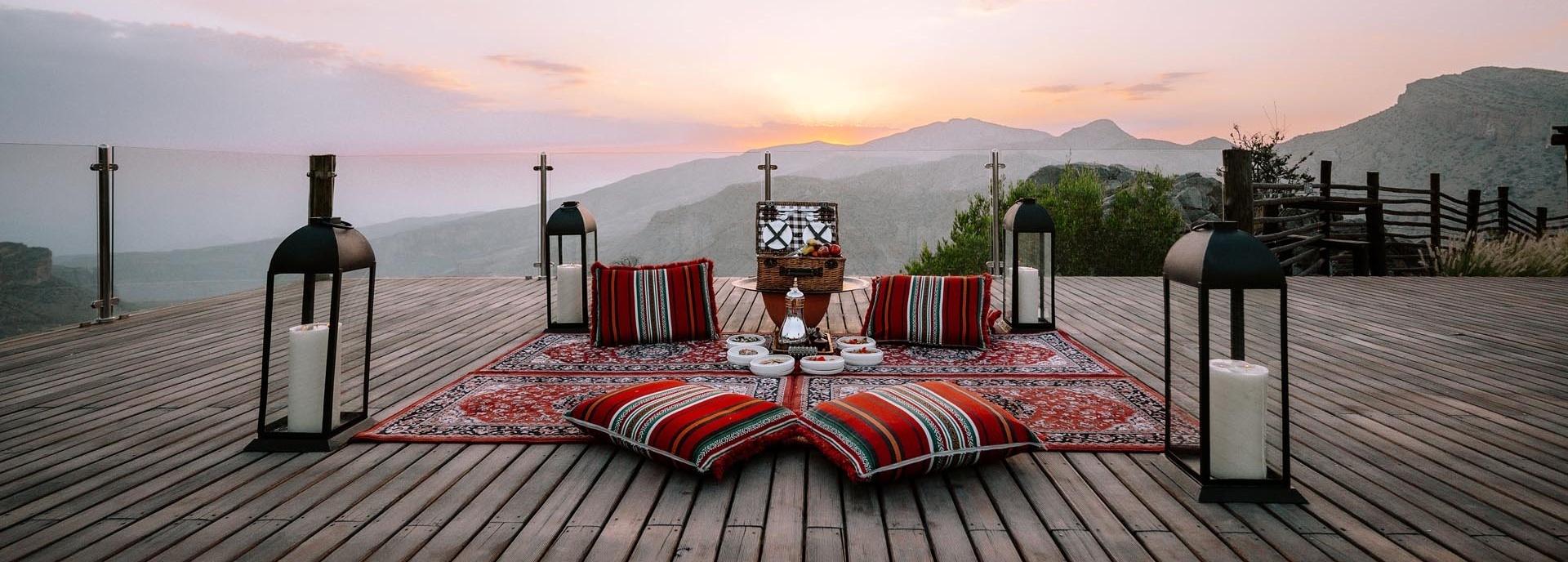 Auf einer Terrasse liegt ein Teppich und darauf steht ein Picknickkorb.