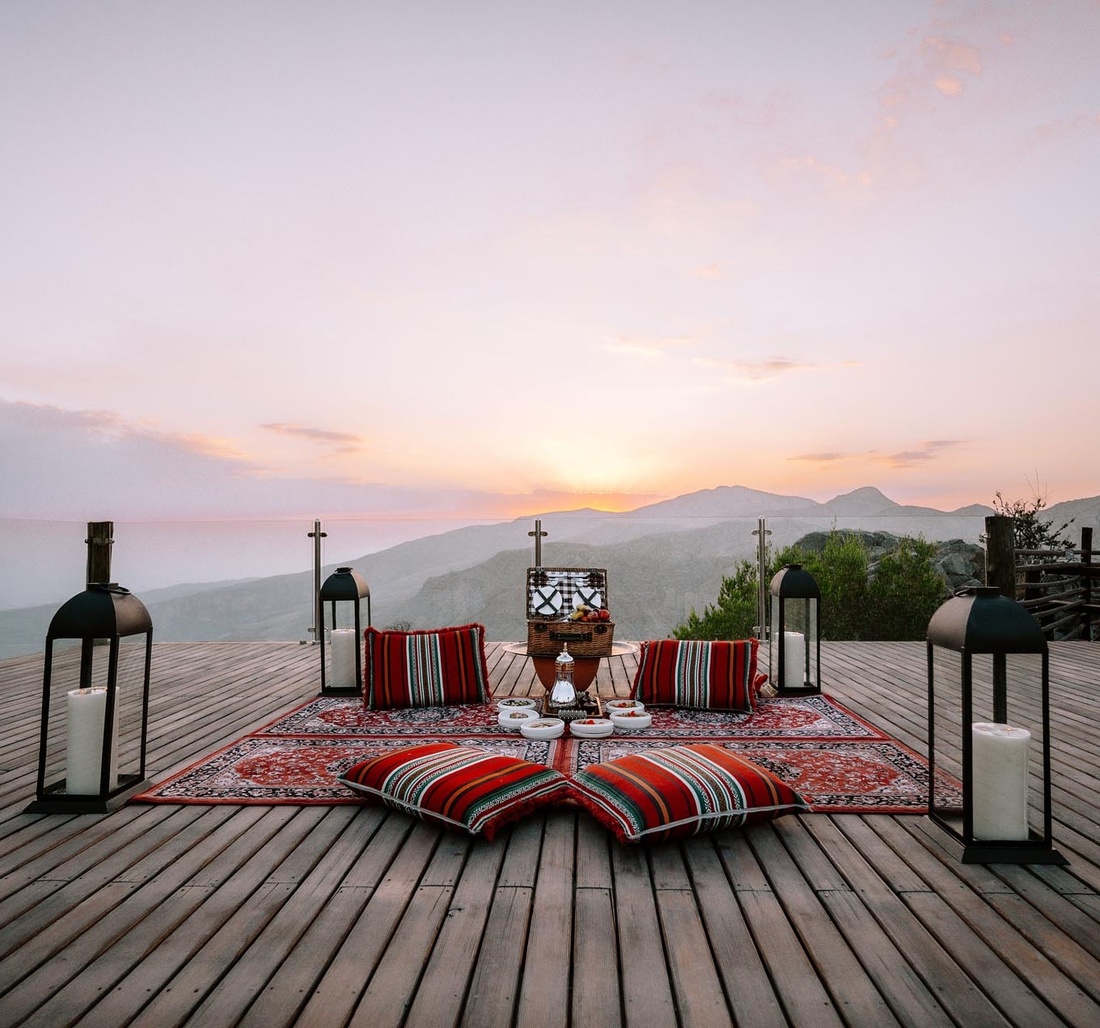 Auf einer Terrasse liegt ein Teppich und darauf steht ein Picknickkorb.