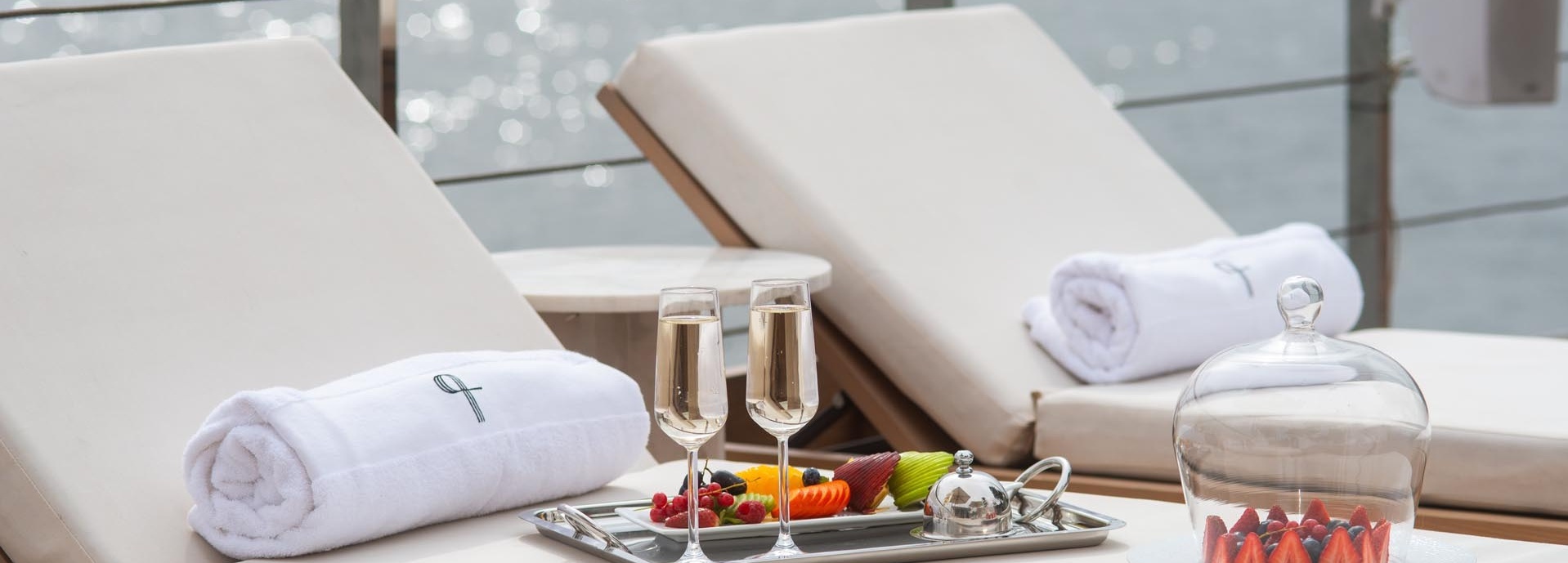 Auf einer Liege stehen zwei Sekt Gläser und ein Früchteteller.