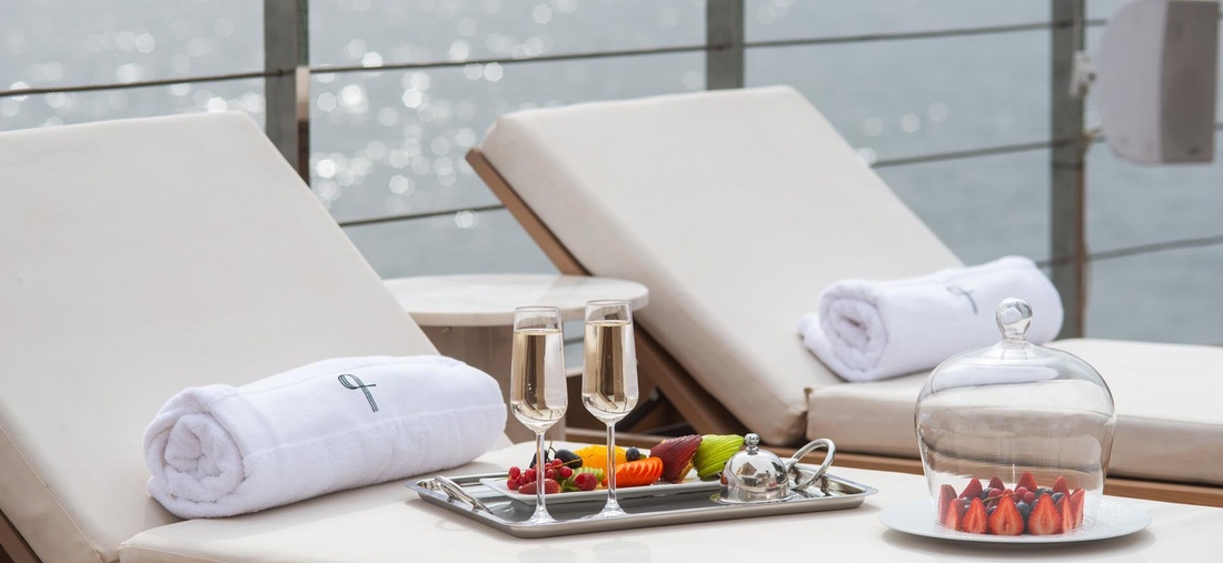 Auf einer Liege stehen zwei Sekt Gläser und ein Früchteteller.