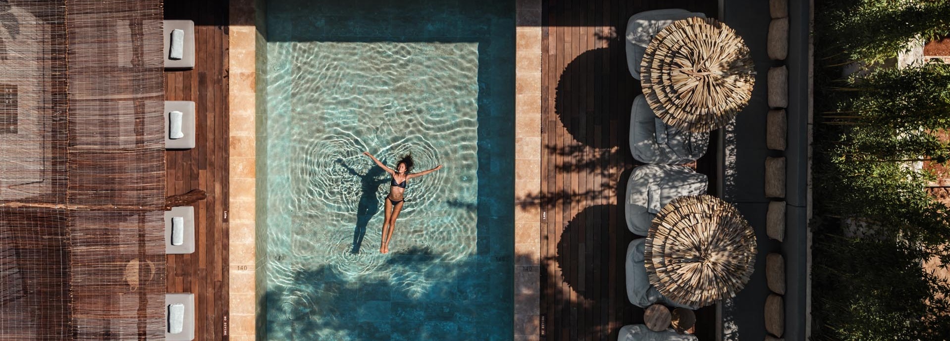 Eine Frau in einem schwarzen Bikini schwimmt im Pool.