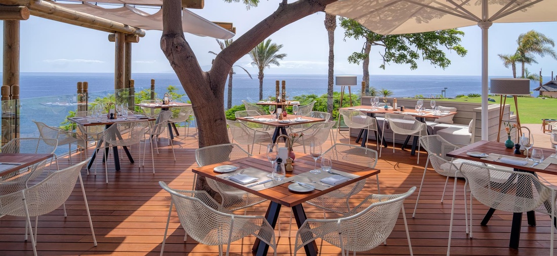 Auf einer Terrasse stehen gedeckte Tische.