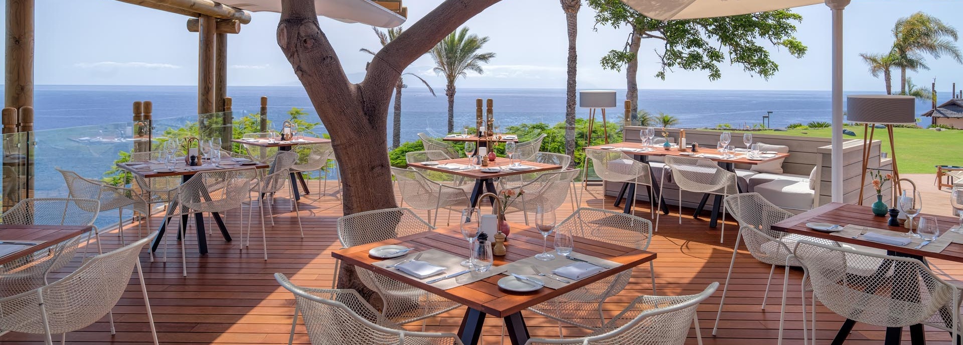 Auf einer Terrasse stehen gedeckte Tische.