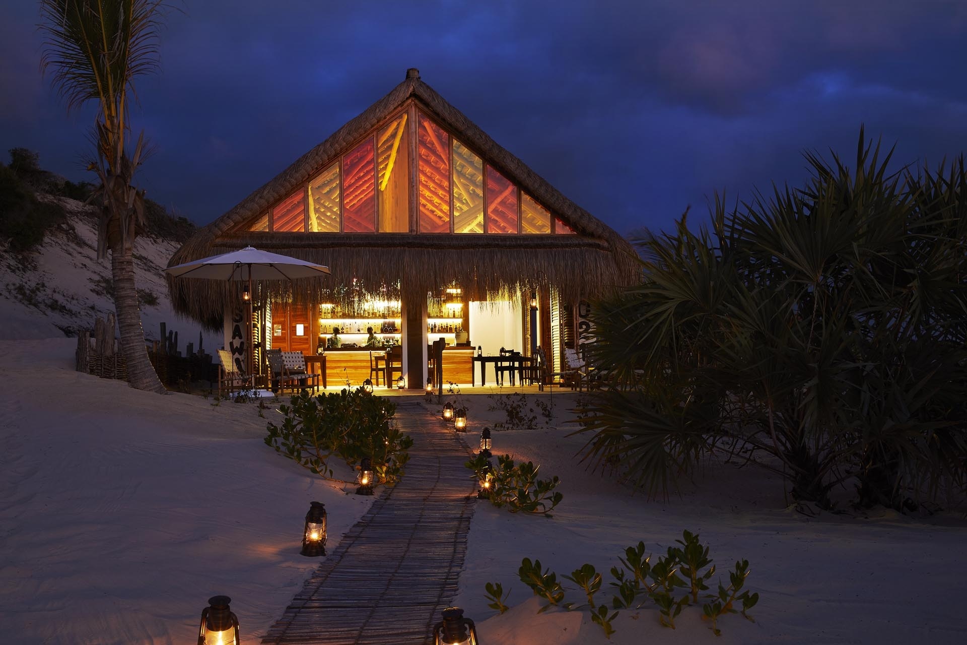 Ein kleines Haus mit einer Bar am Strand.