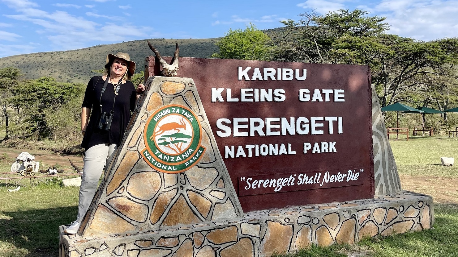 Eine Frau steht neben dem Schild eines National Parks.