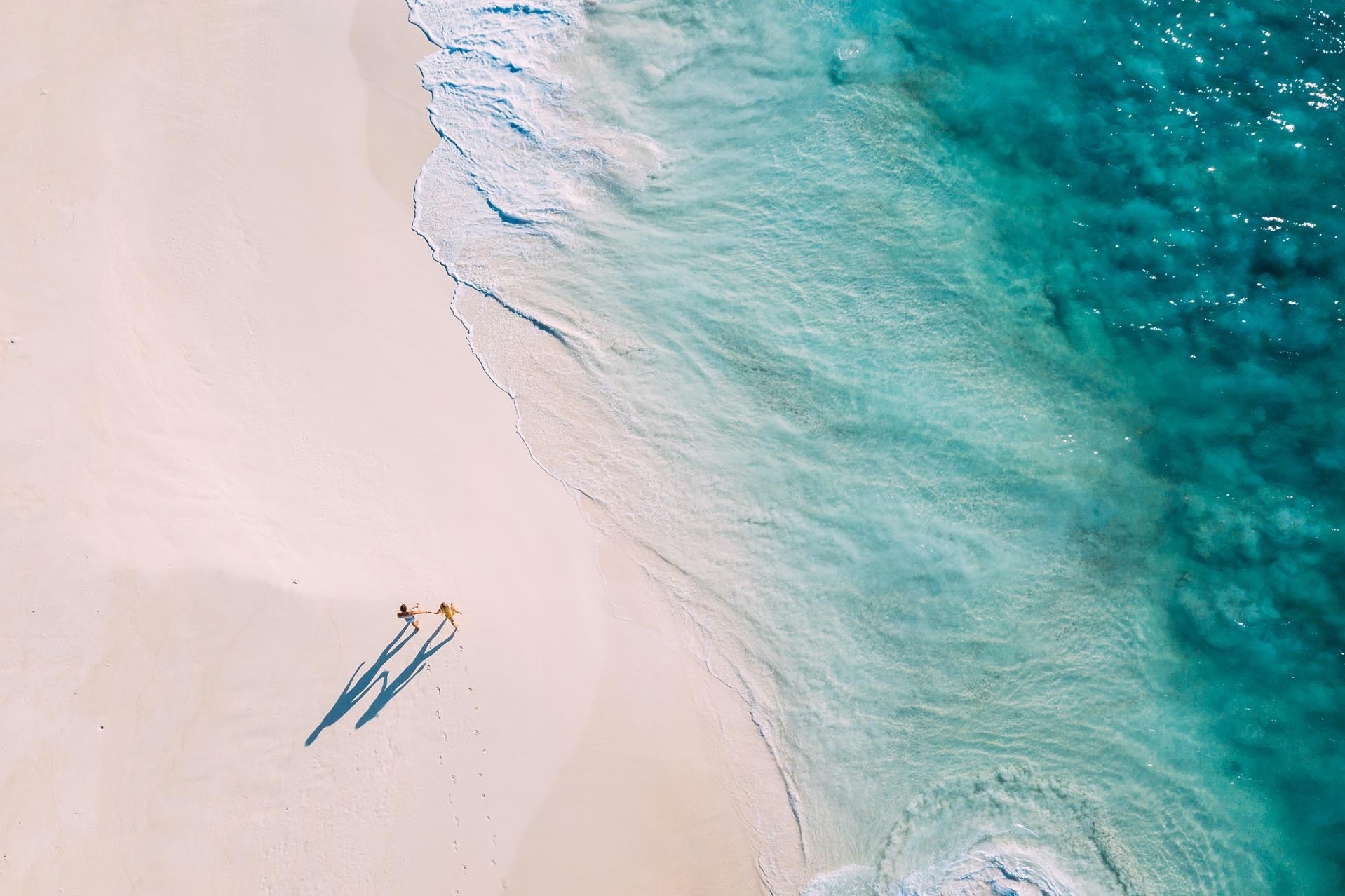 Ein Mann und eine Frau spazieren Hand in Hand am Strand.