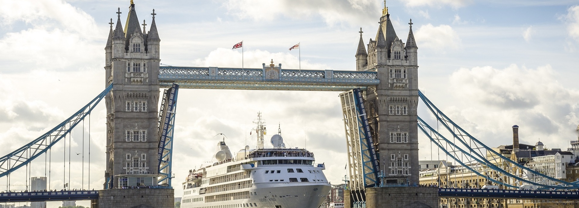 Ein Kreuzfahrtschiff fährt unter einer Brücke durch.