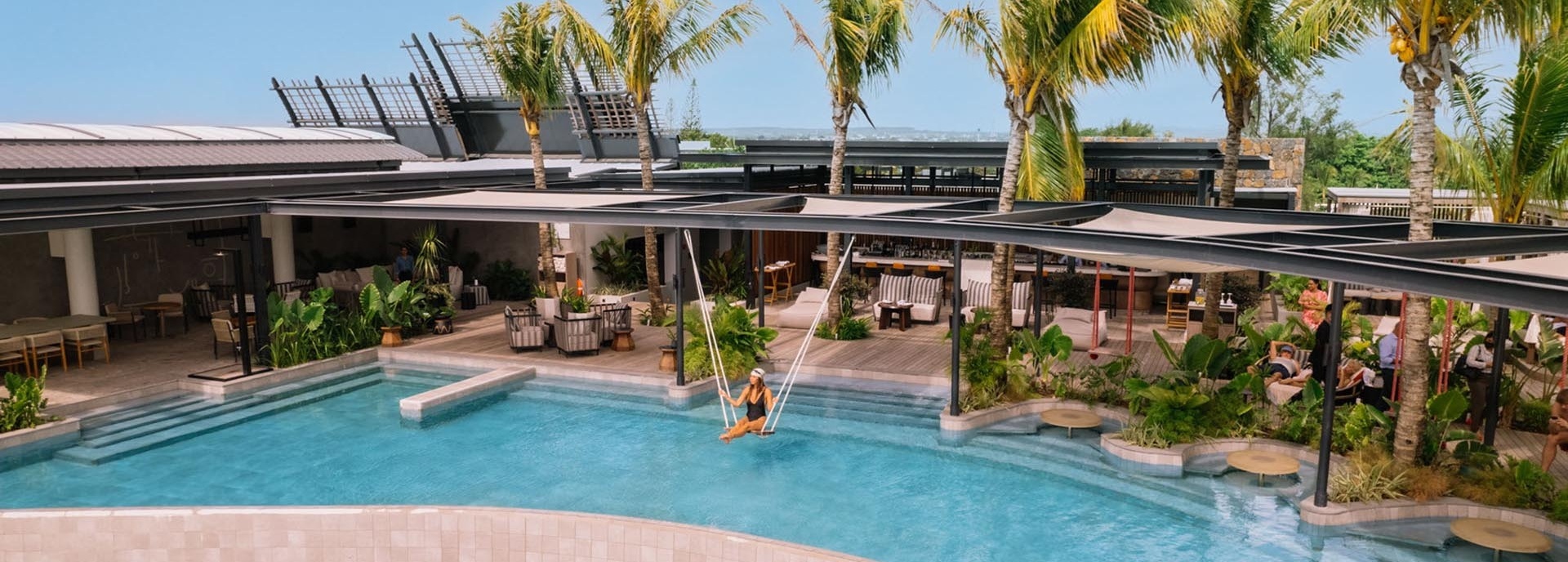 Eine Frau schaukelt auf einer Schaukel, über einem Pool.