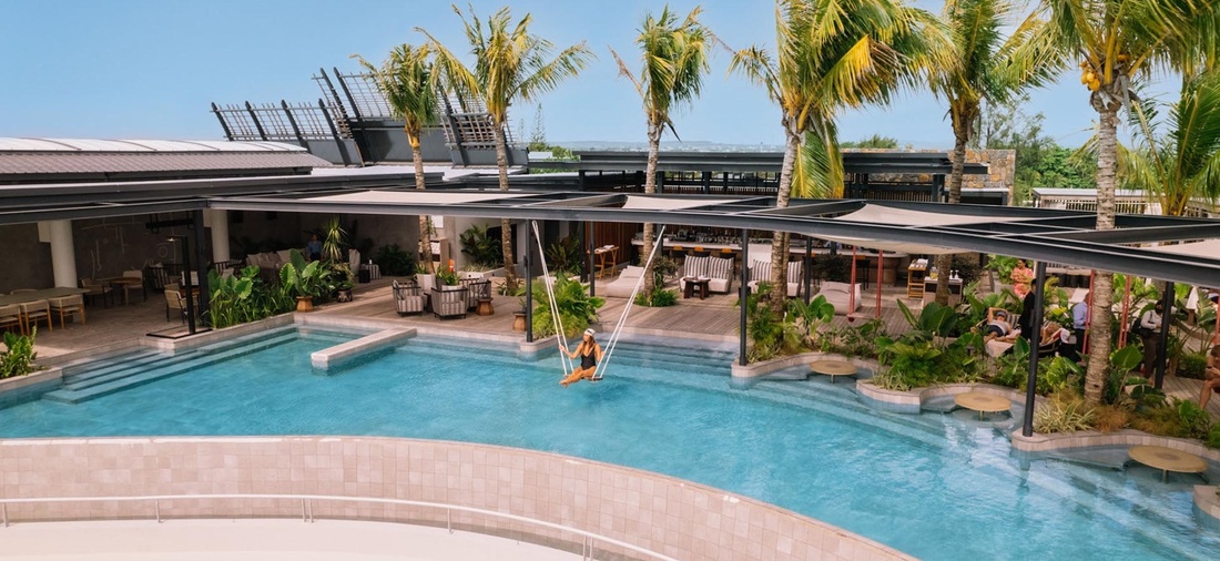 Eine Frau schaukelt auf einer Schaukel, über einem Pool.