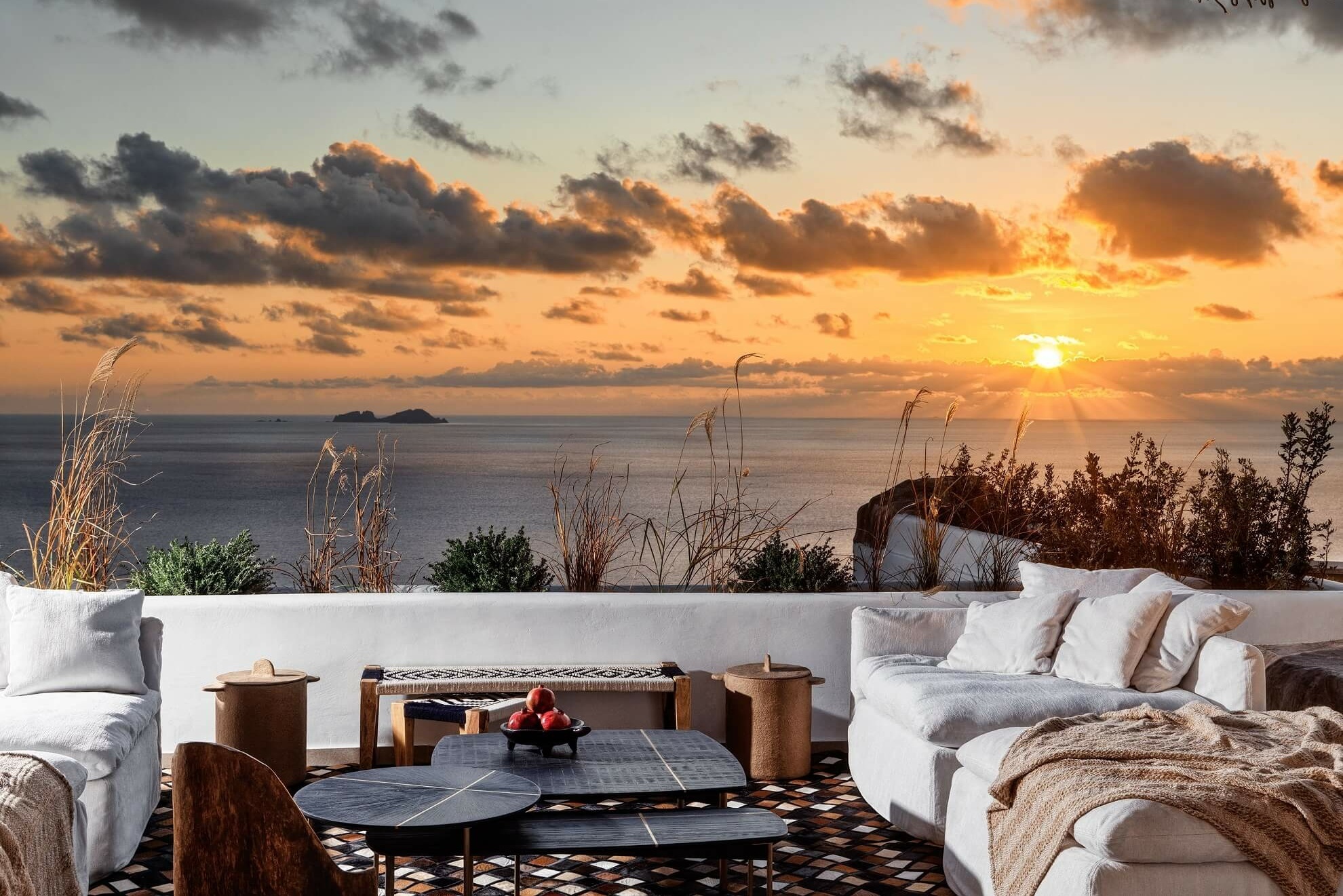 Terrasse einer Villa mit Sonnenuntergang im Hintergrund.