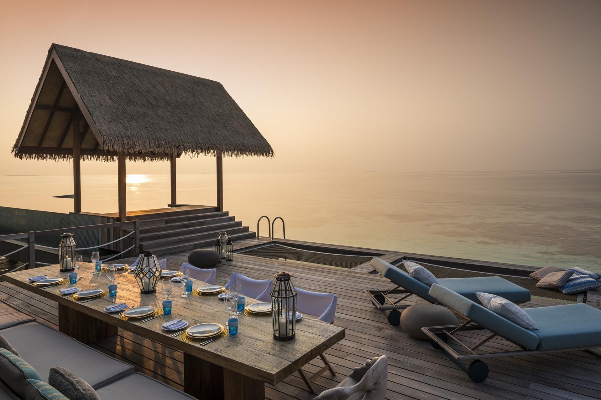 Ein gedeckter Tisch steht auf einer Terrasse am Wasser.