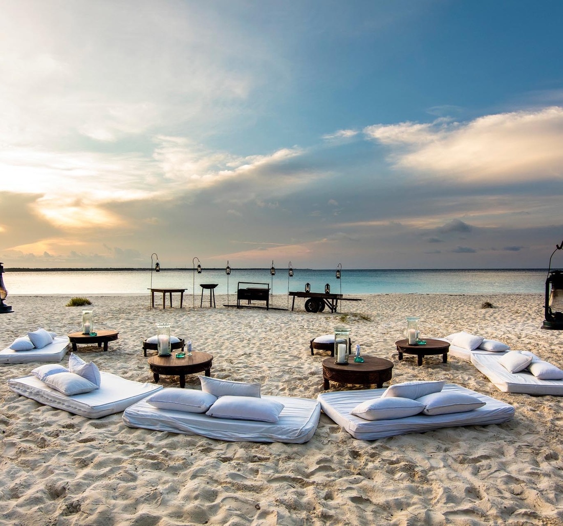 Kleine Tische und mehrere Sitzmöglichkeiten am Strand.