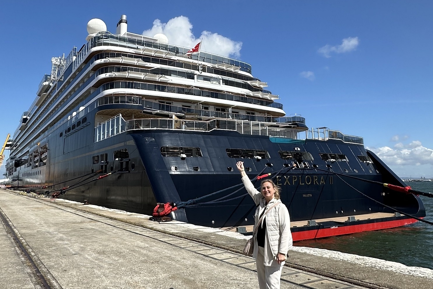 Eine Frau steht vor einem großen Kreuzfahrtschiff.