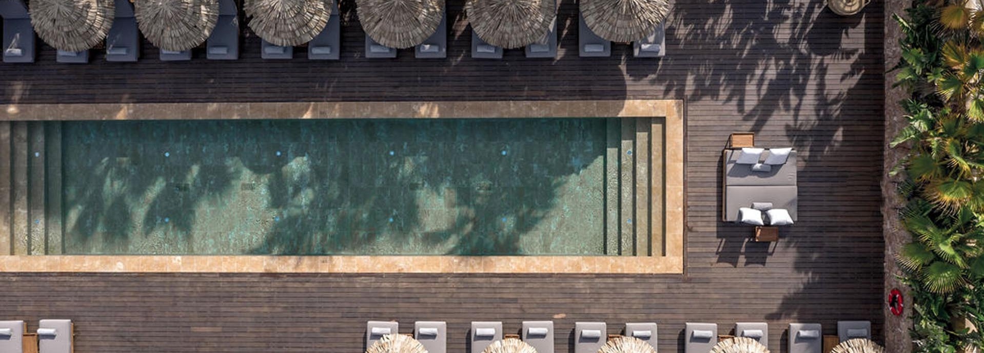 Ein Pool umgeben von Sonnenliegen und Sonnenschirmen.