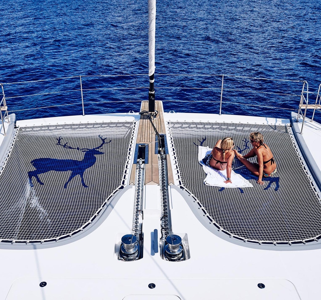 Zwei Frauen in Bikinis entspannen am Deck eines Schiffes.