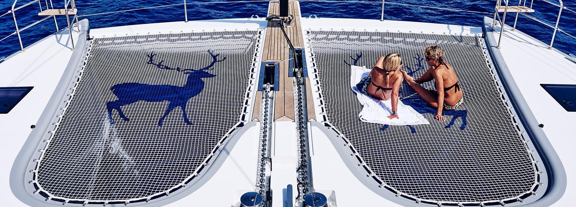 Zwei Frauen in Bikinis entspannen am Deck eines Schiffes.