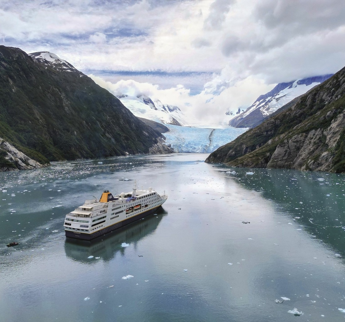 Ein Kreuzfahrtschiff fährt auf einen Gletscher zu.