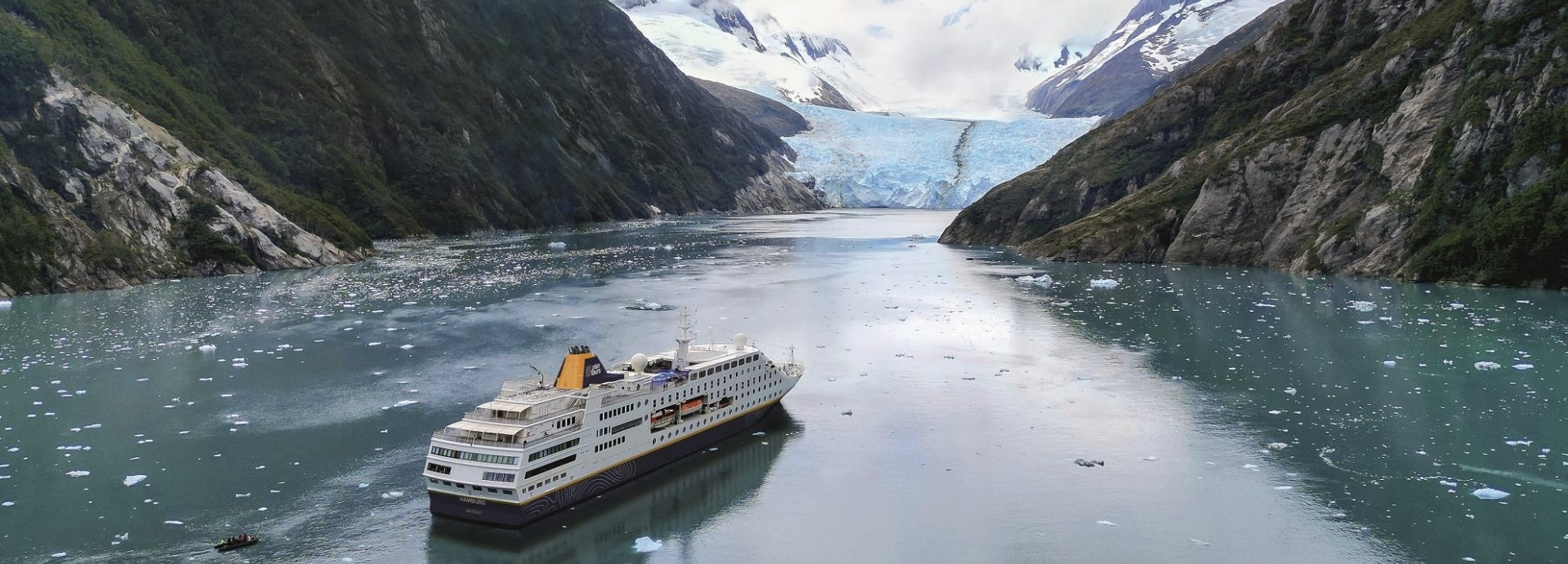 Ein Kreuzfahrtschiff fährt auf einen Gletscher zu.