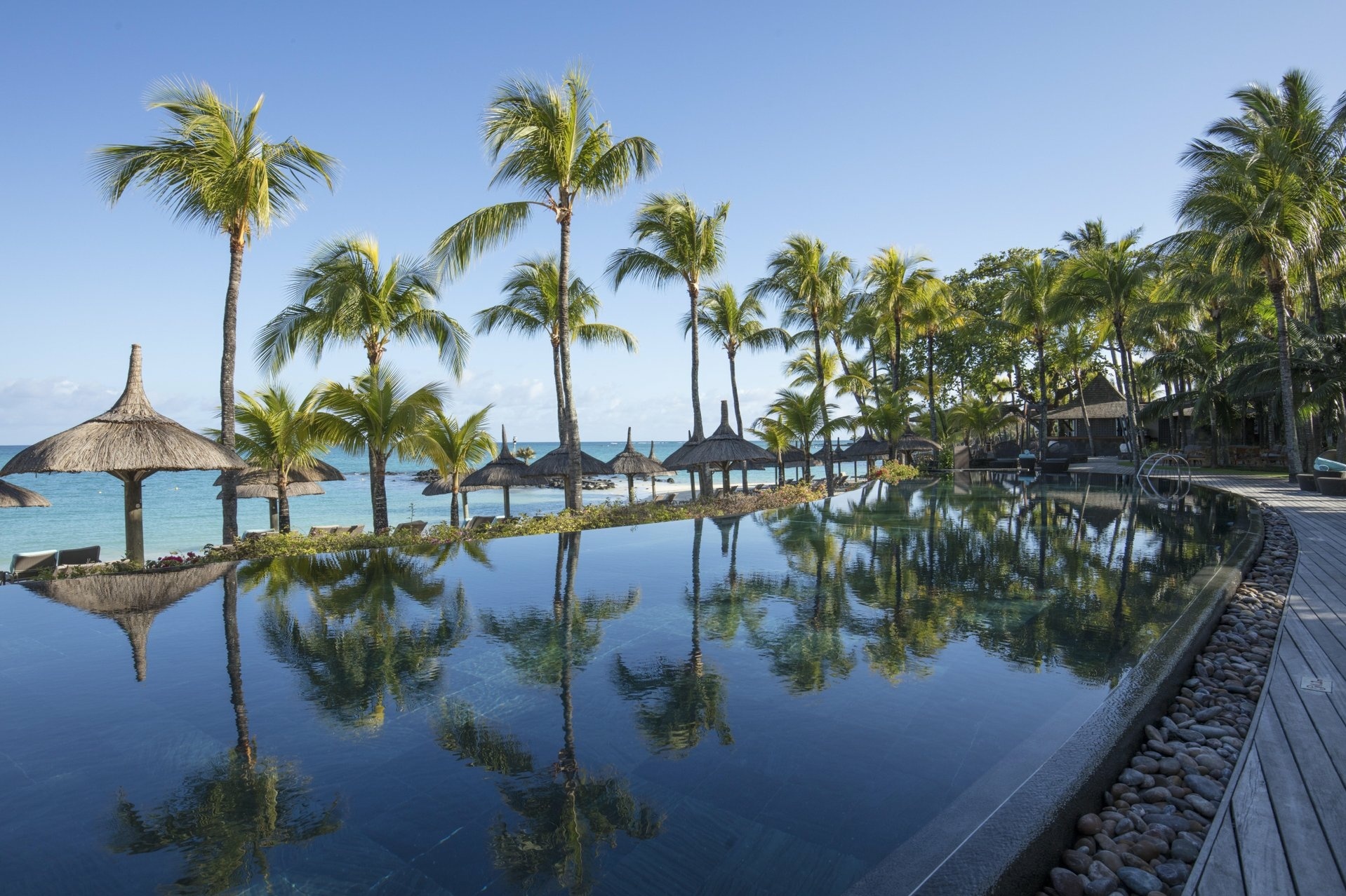 Pool mit Palmen direkt am Meer
