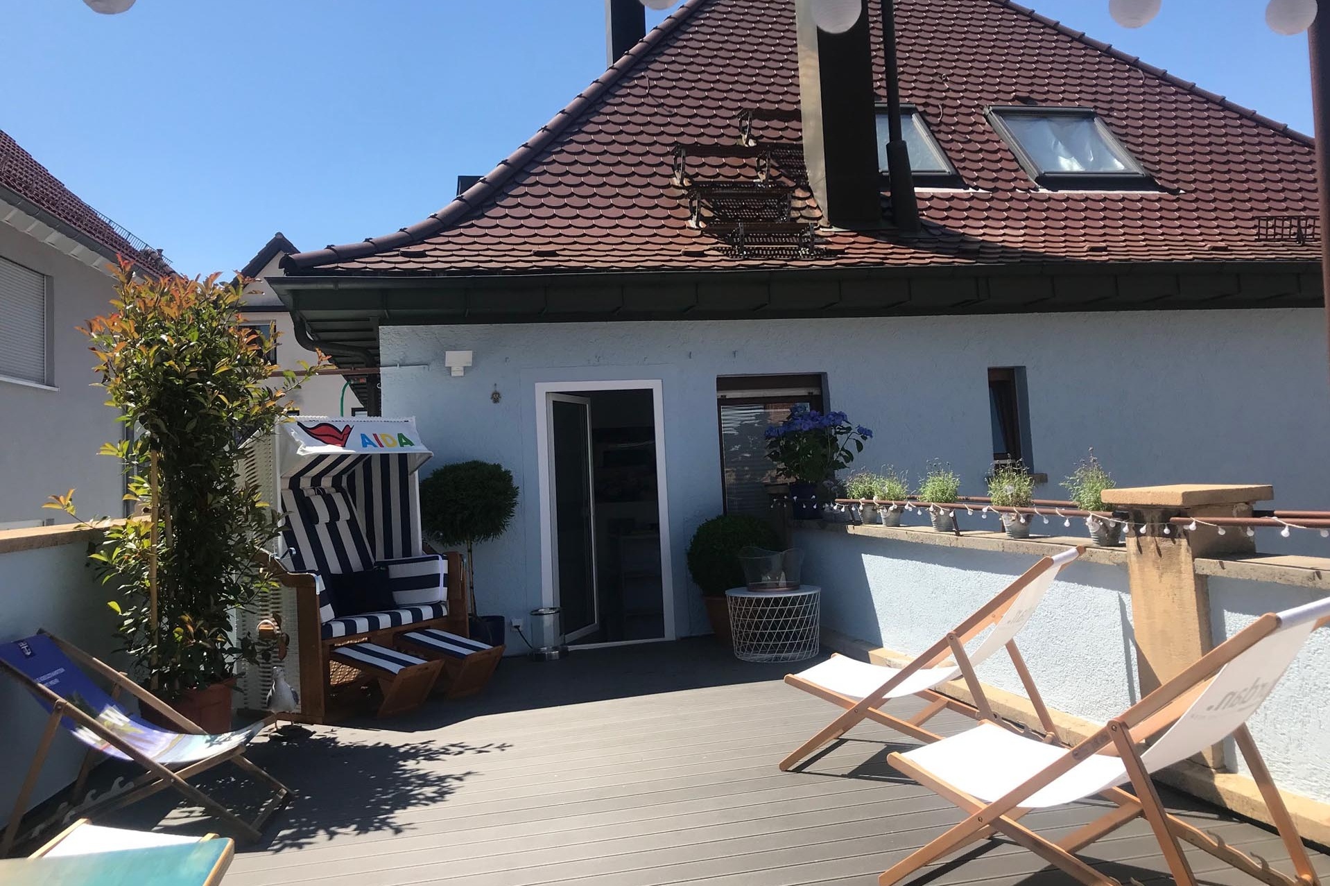 Drei Liegestühle und ein Strandkorb auf einer Terrasse.