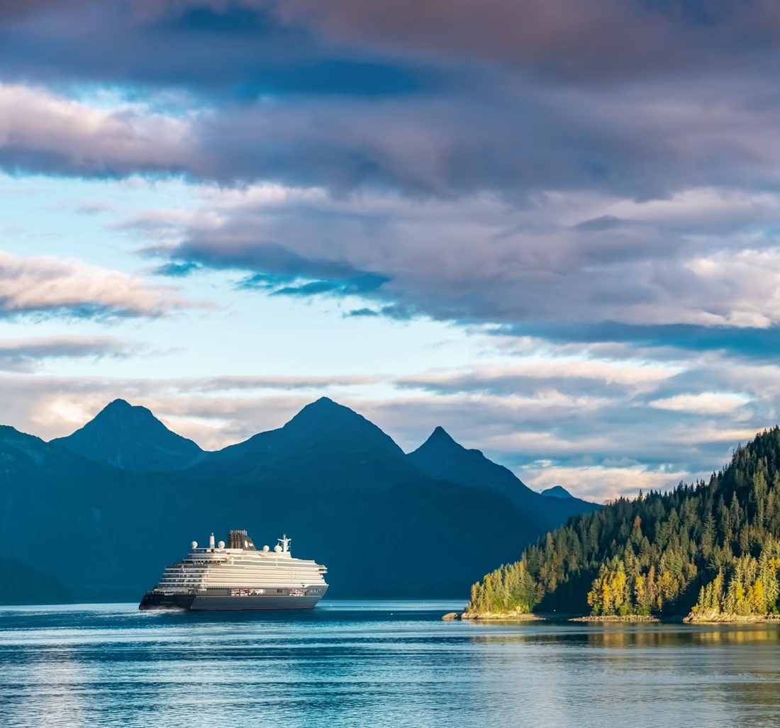 Ein großes Schiff fährt an einer Insel vorbei.