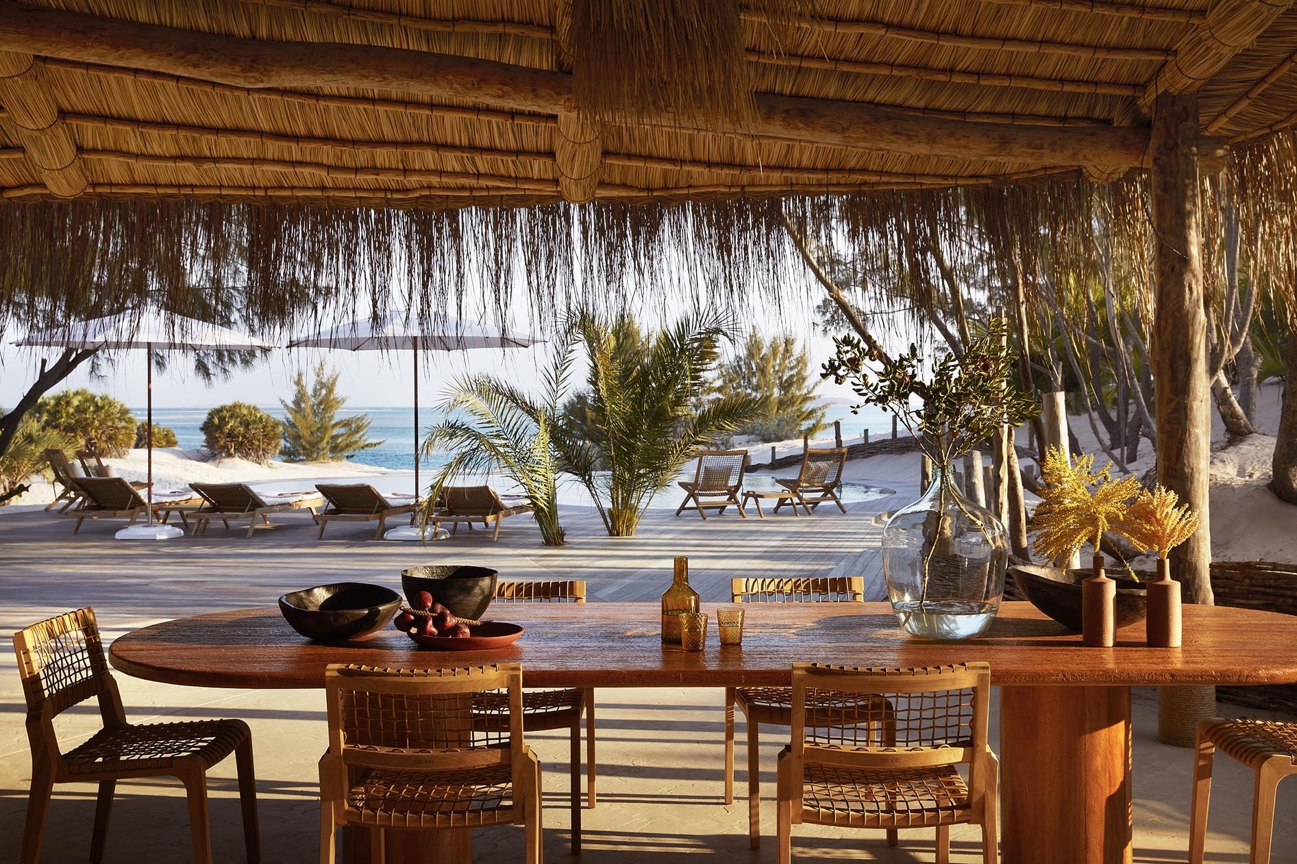 Eine Terrasse mit Liegen, Tischen und Stühlen am Strand.