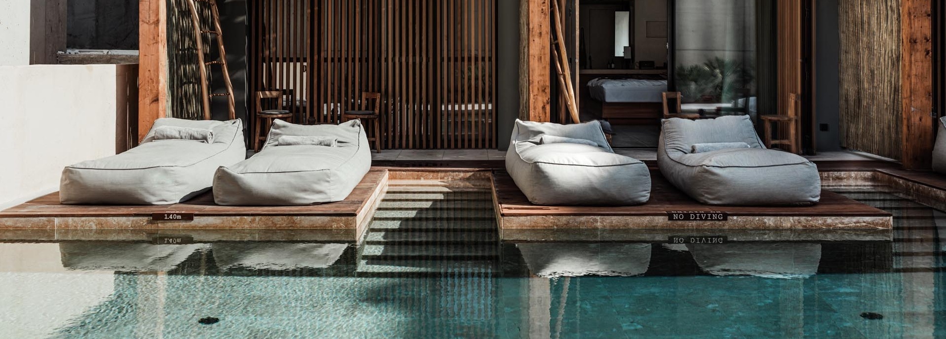 Vor einem Pool stehen vier Sitzsäcke.