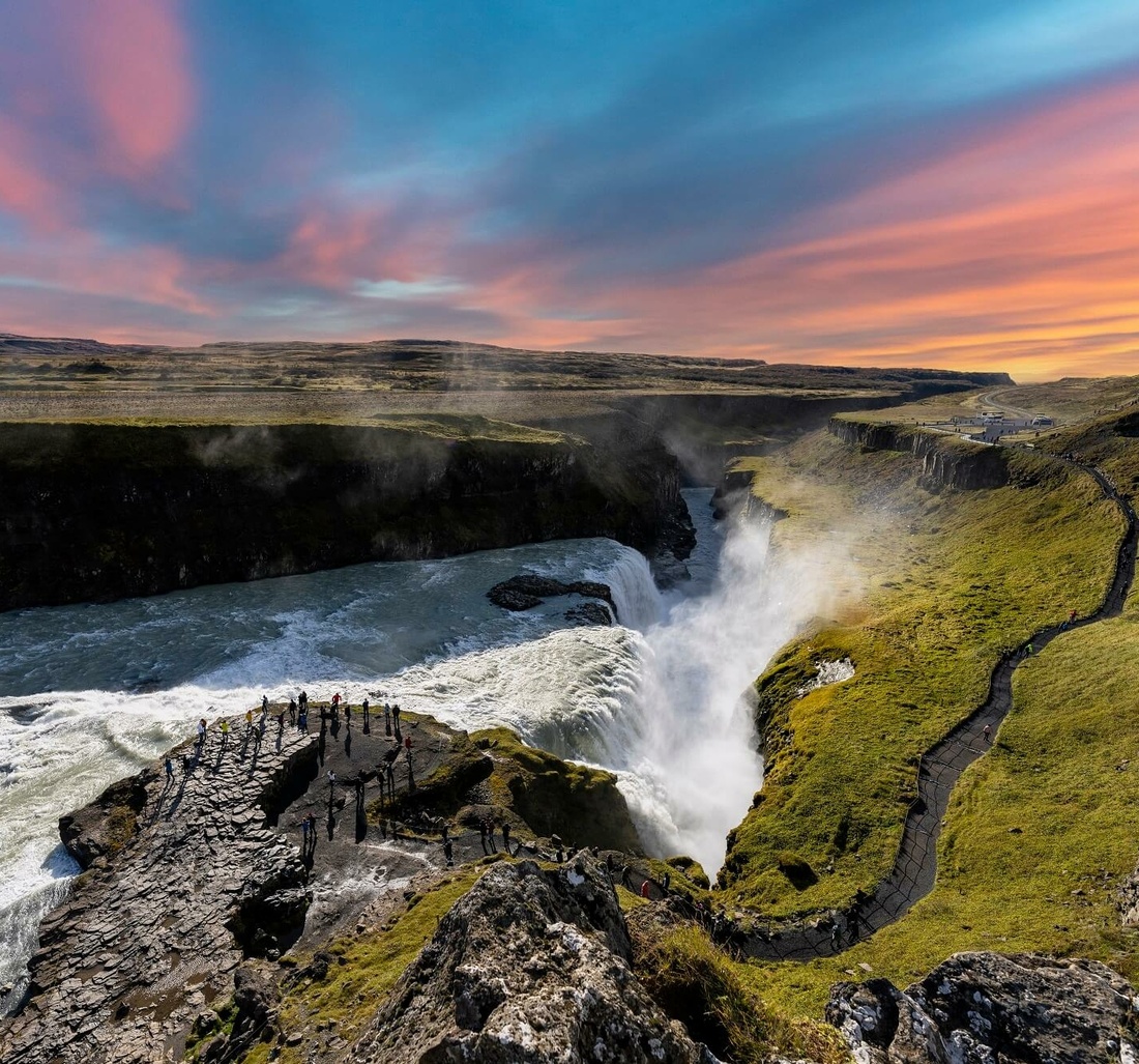 Touristen stehen neben einem großen Wasserfall.