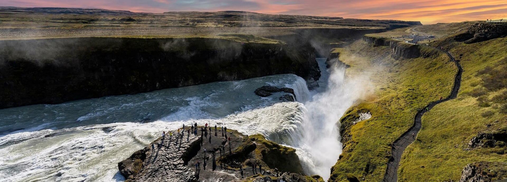 Touristen stehen neben einem großen Wasserfall.