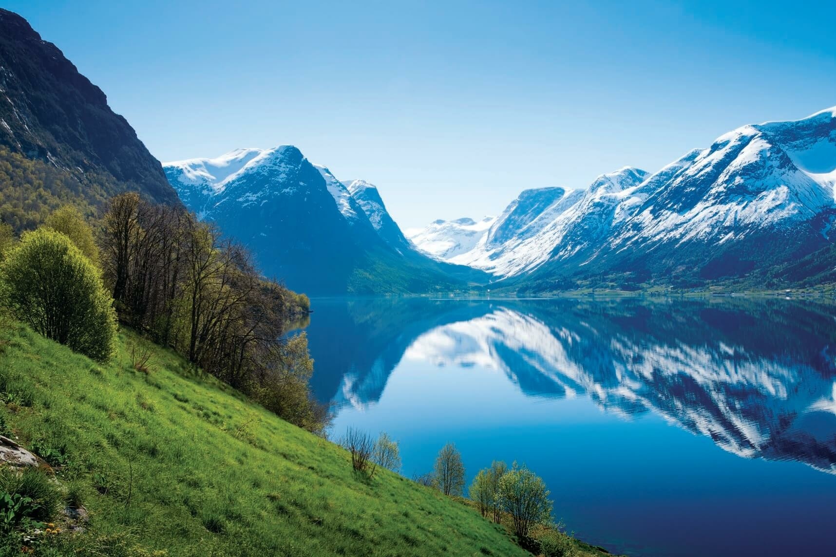 Ein Fluss mit einer verschneiten Berglandschaft im Hintergrund.