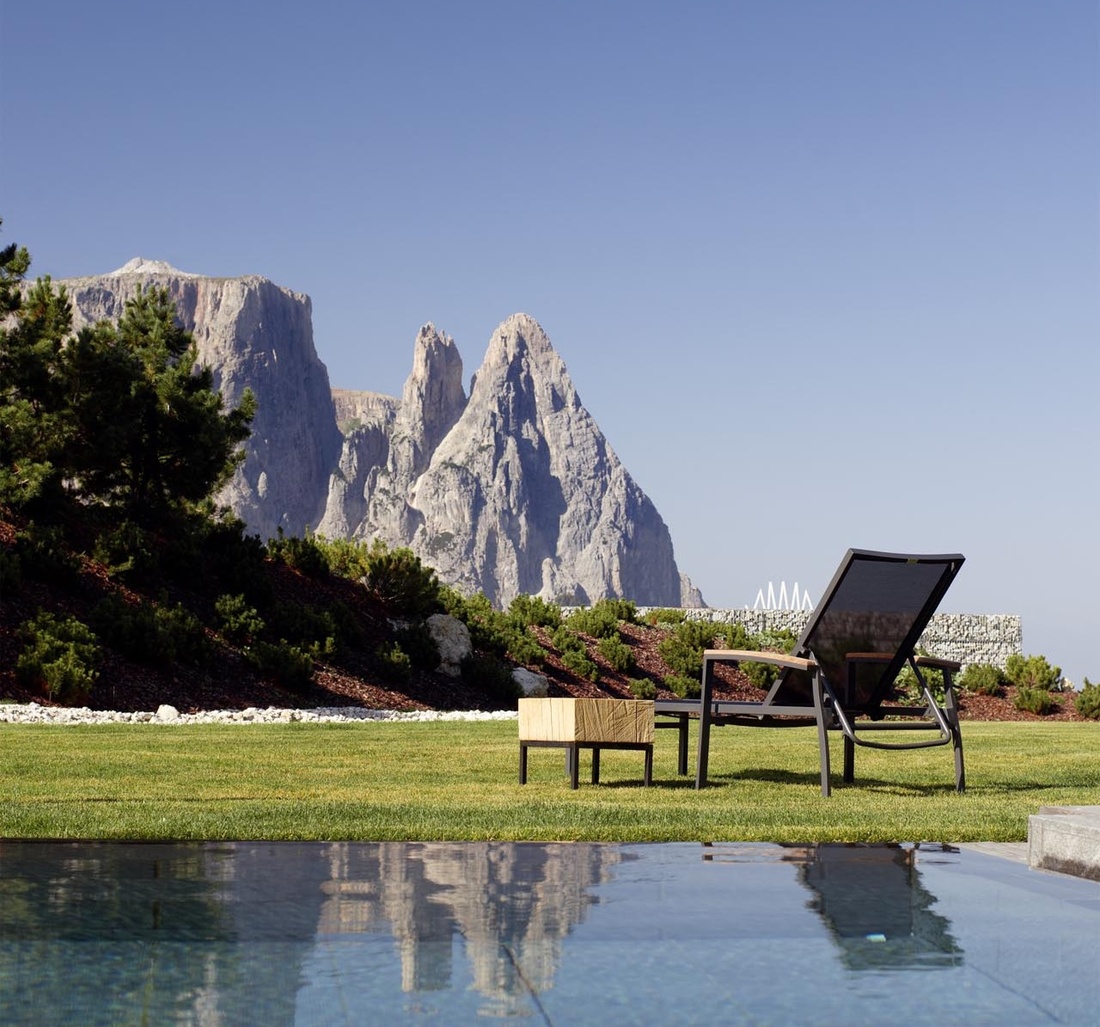 Ein Stuhl steht auf einer Wiese vor einem Pool.