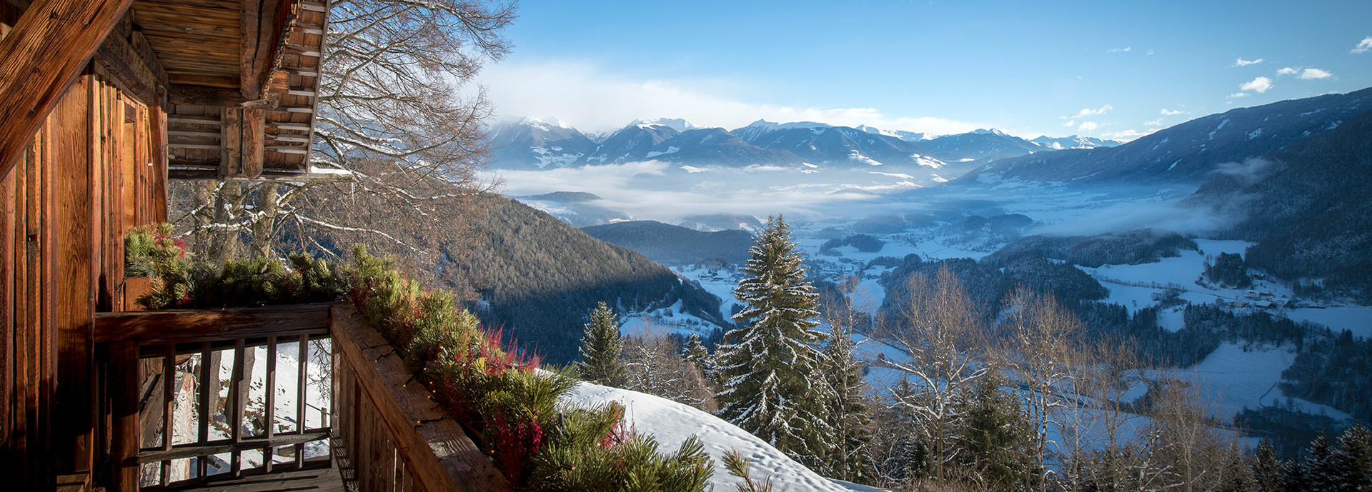Eine Holzhütte vor einer verschneiten Bergkulisse.