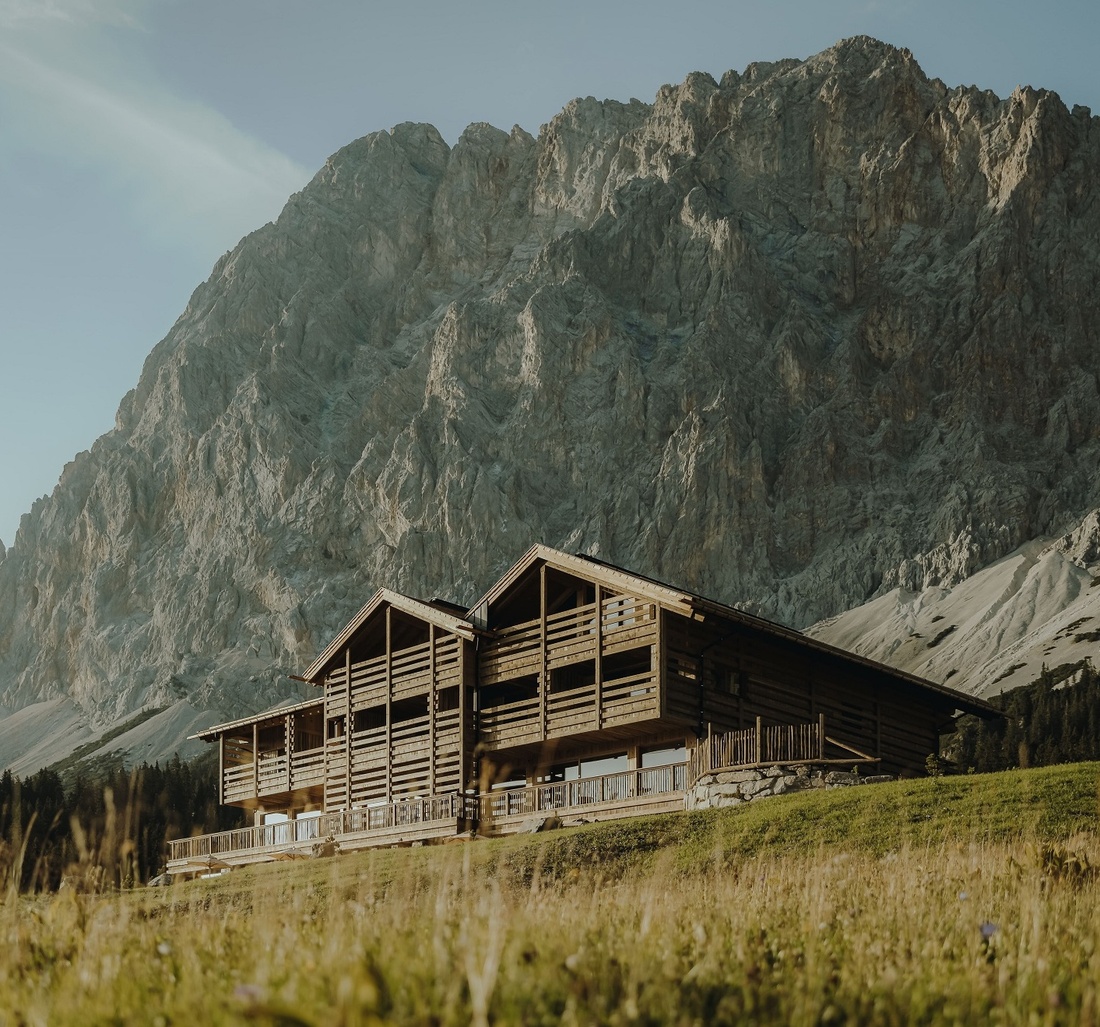 Blick auf ein Hotel vor einer Bergkulisse.