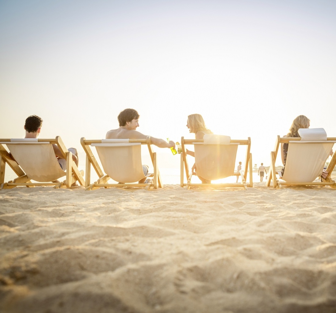 Personen sitzen auf Sonnenstühlen und unterhalten sich.