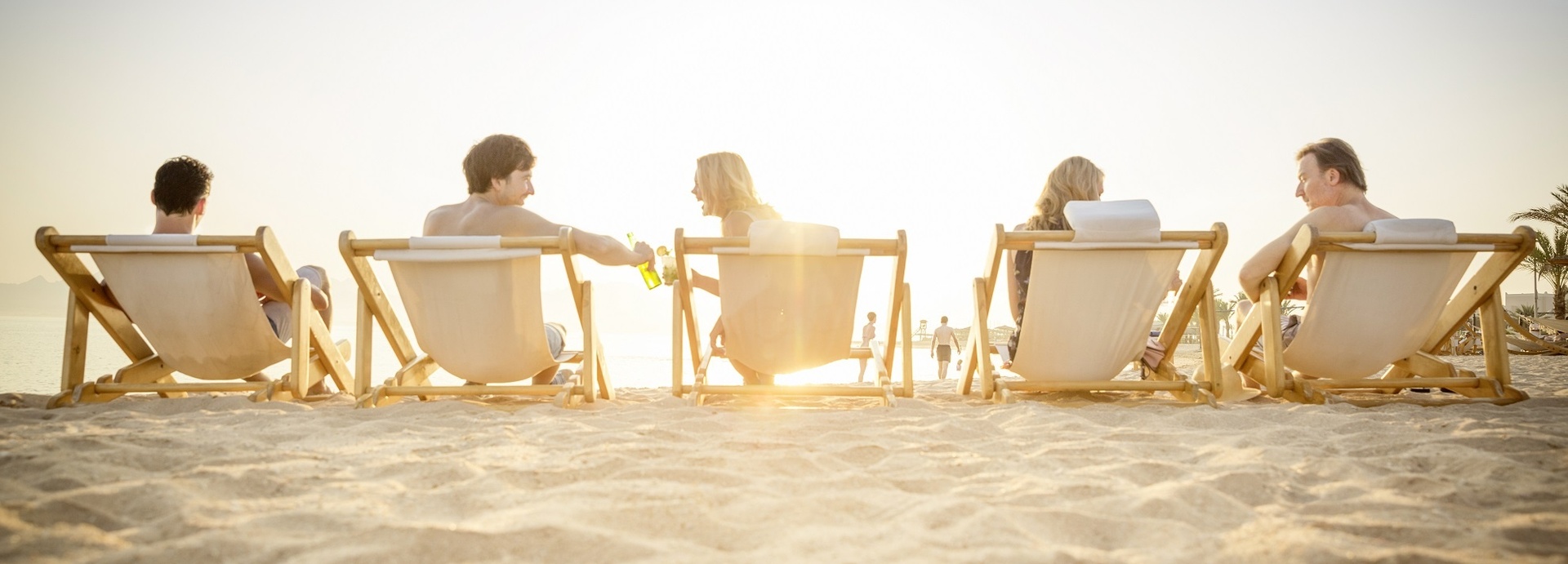 Personen sitzen auf Sonnenstühlen und unterhalten sich.