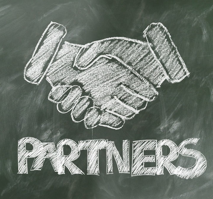 Auf einer grünen Tafel, sind mit Kreide ein Handschlag und der Schriftzug Partners gezeichnet.