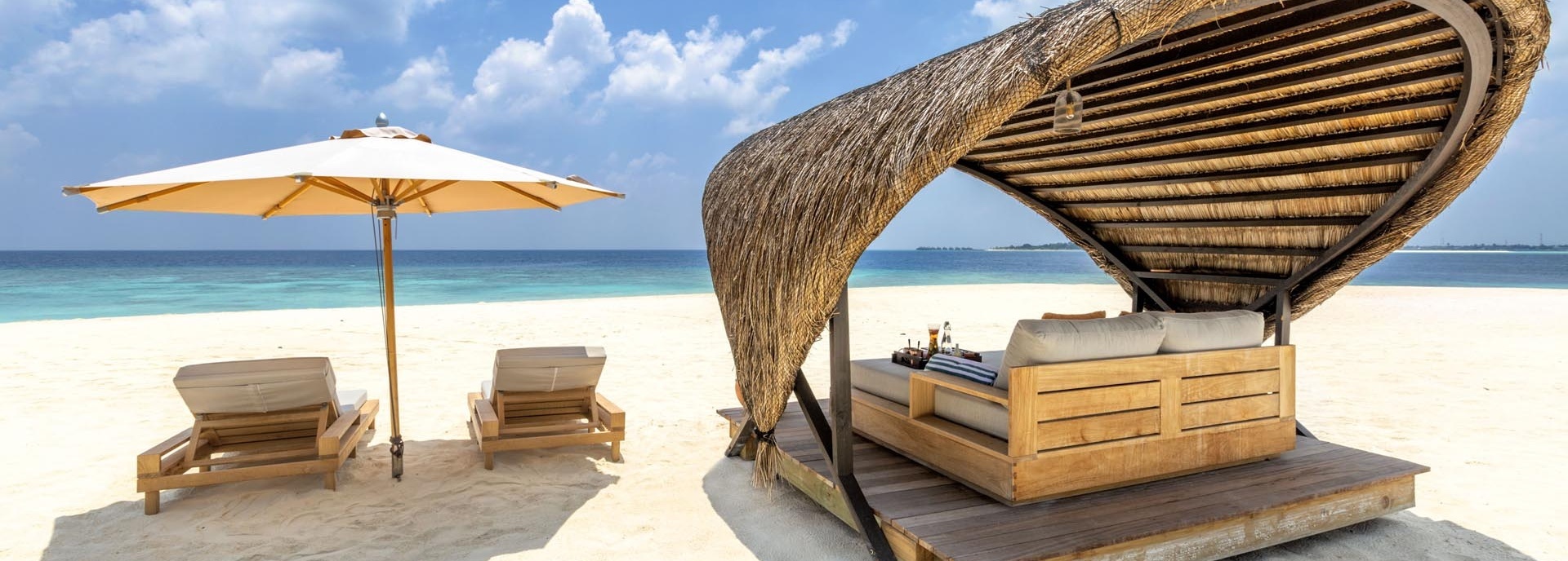 Zwei Liegen und eine Doppelliege am Strand.