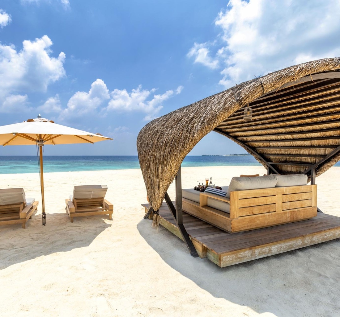 Zwei Liegen und eine Doppelliege am Strand.