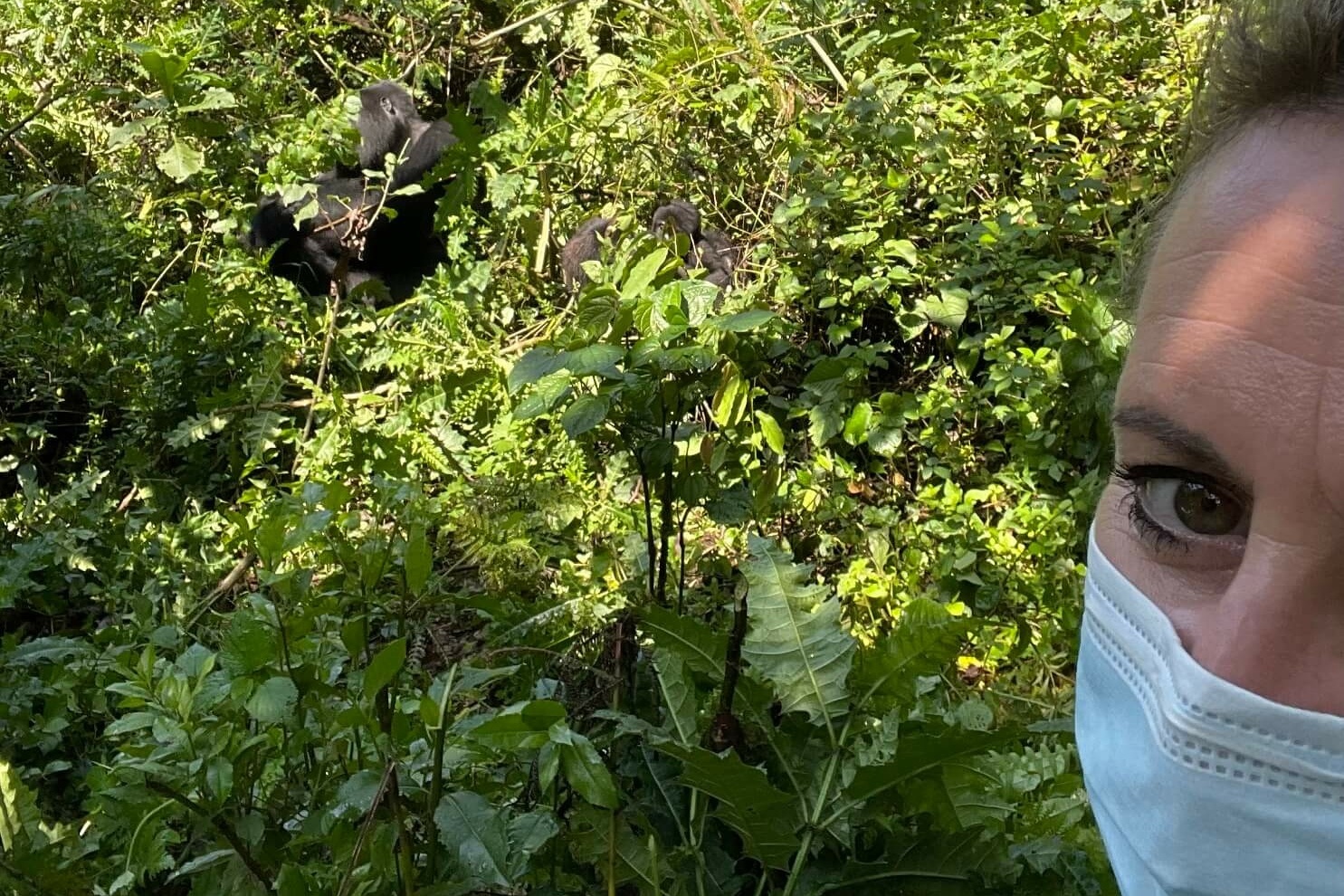Eine Frau mit einer Maske, fotografiert ein Tier in der Wildnis.