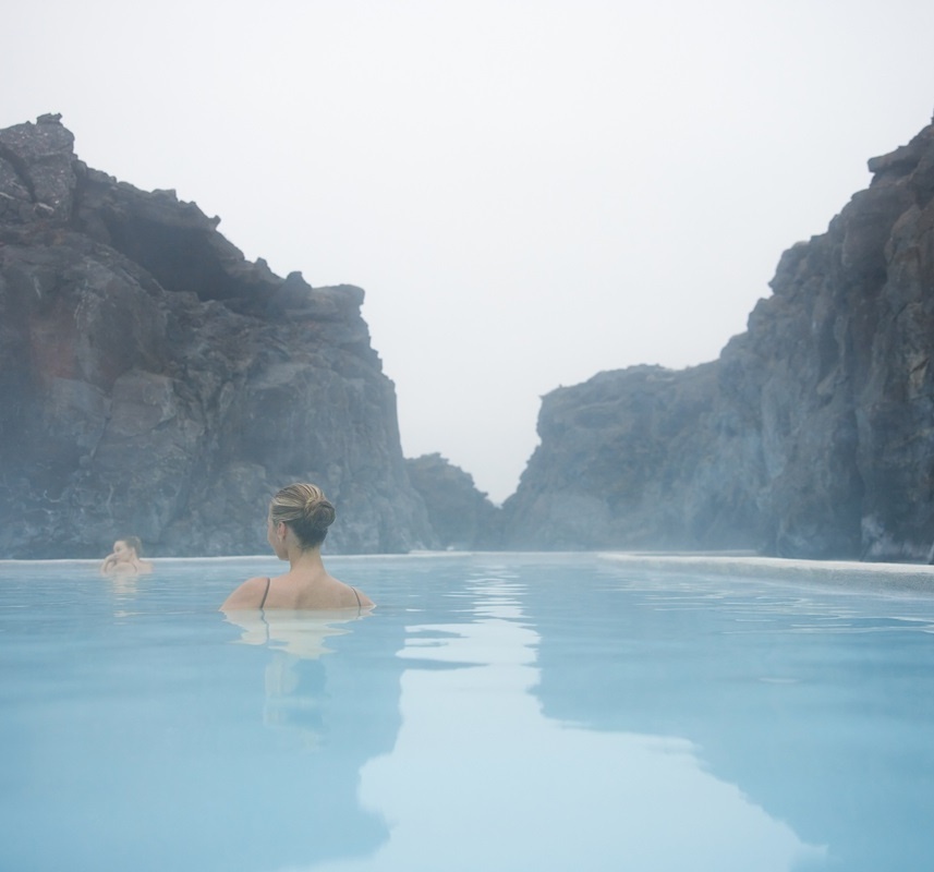 Eine Frau schwimmt in einer blauen Lagune.