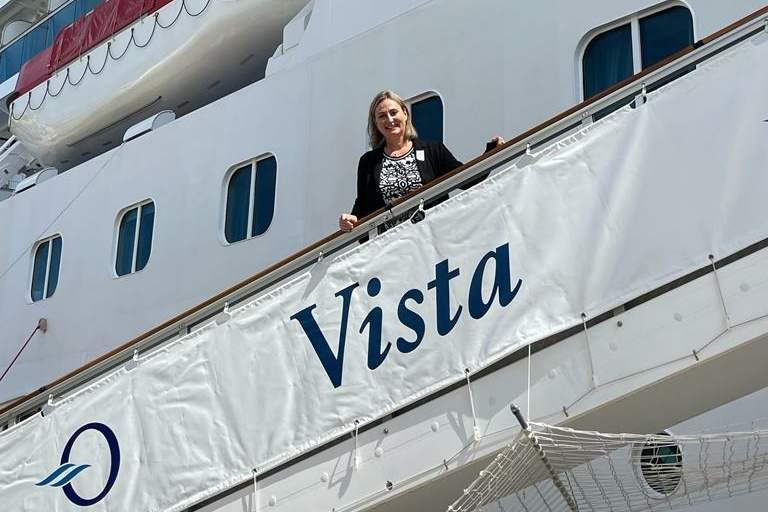 Eine lachende Frau steht auf einem Kreuzfahrtschiff.